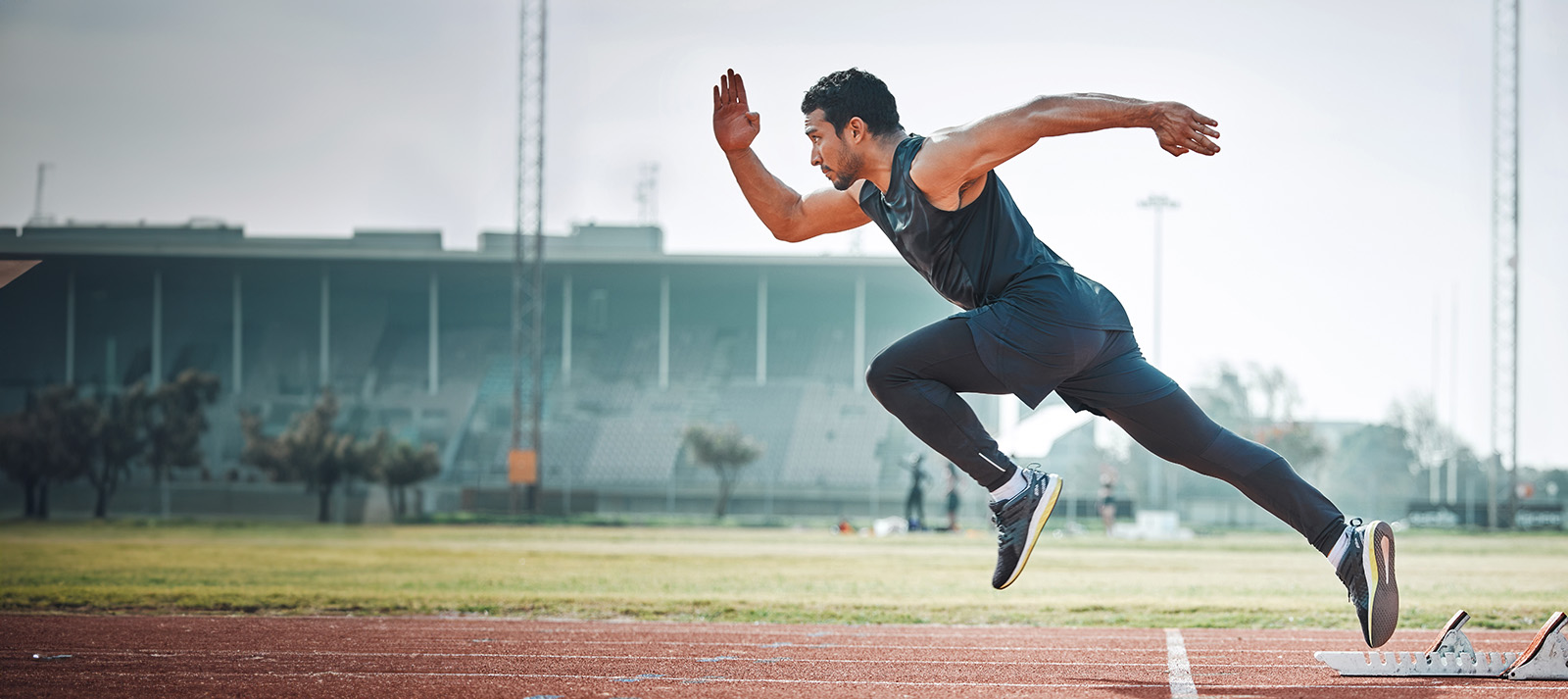 A man in athletic attire running on a track with a blurred background.