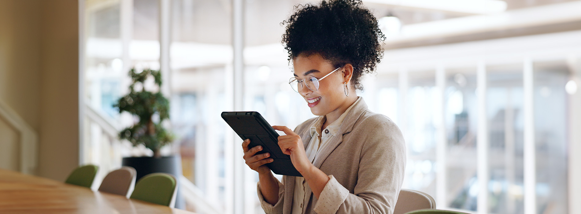 Woman sitting at table using tablet computer with smile on face.